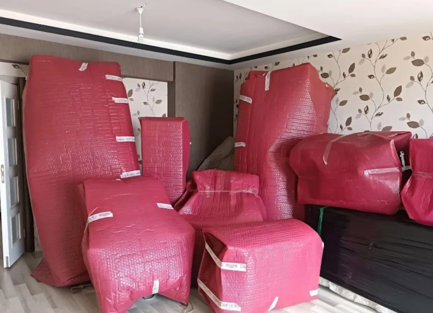 Balonlu naylonla sarılıp bantlanmış koltuk takımı ve dolap parçaları, taşınmaya hazır salon